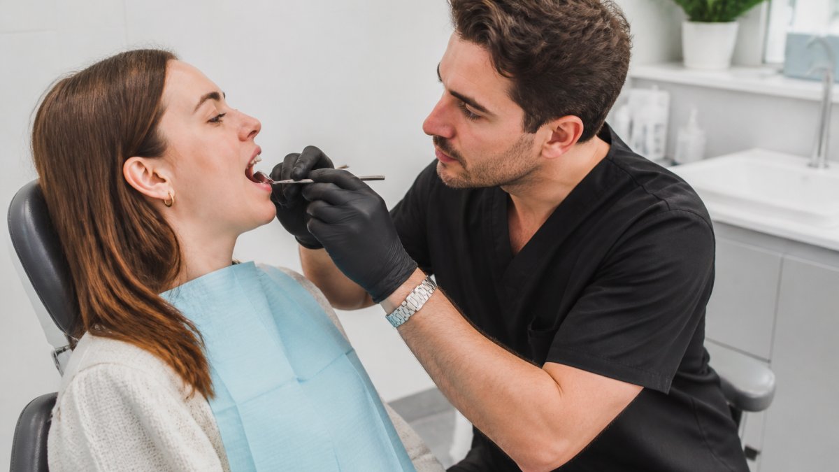 Professional demonstrating early warning signs of tooth decay examination in modern clinical setting with natural lighting