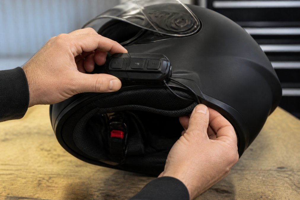 Rider mounting a Bluetooth control unit to a motorcycle helmet during setup