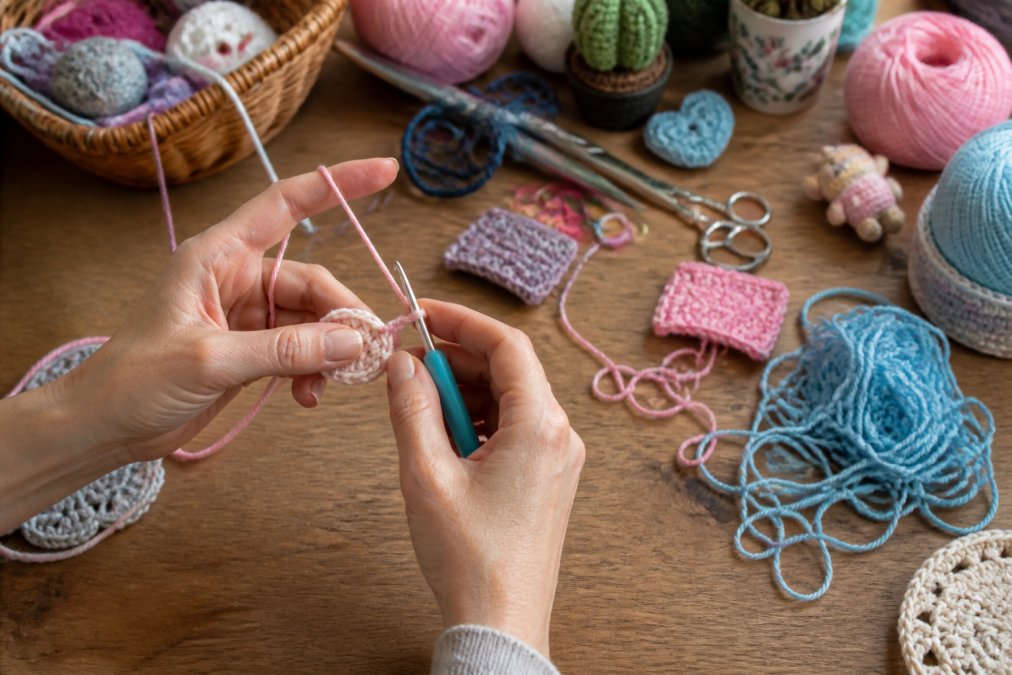 Close-up of hands holding crochet hook and yarn, demonstrating proper grip with relaxed fingers and yarn tension control positioned around hand