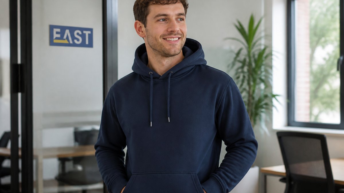 Professional team member wearing navy embroidered hoodie with company logo on chest, showing detailed stitch quality and professional finish in modern office setting