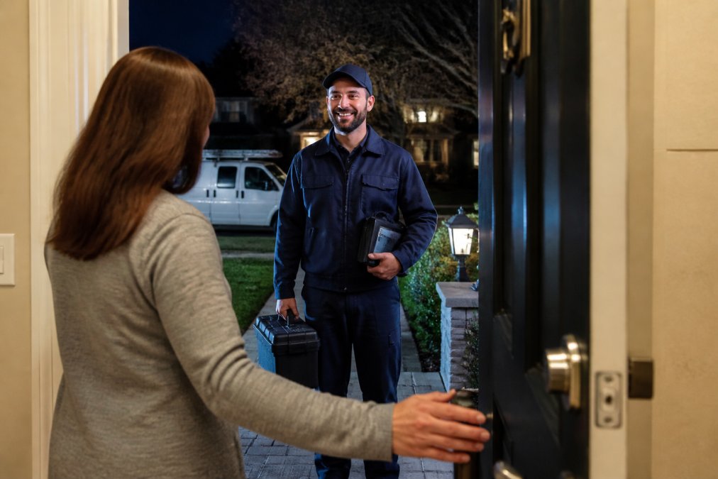 Homeowner greeting an emergency HVAC repair technician at their front door at night