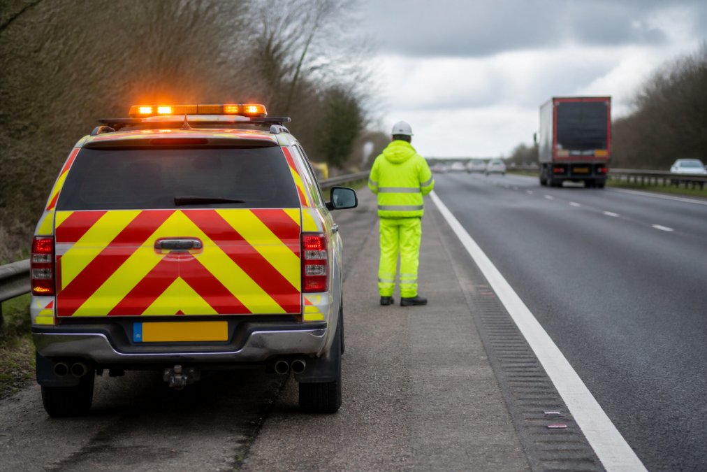 Emergency Light Requirements for Fleet Managers: 2026 Guide Fleet vehicle parked on motorway shoulder with amber beacon activated, hazard lights flashing, and high-visibility personnel standing safely at roadside distance