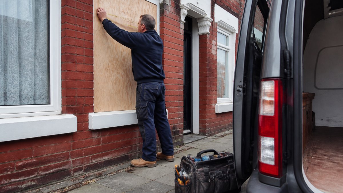Glazier installing plywood for emergency window boarding services Leicester at a damaged terraced house window.