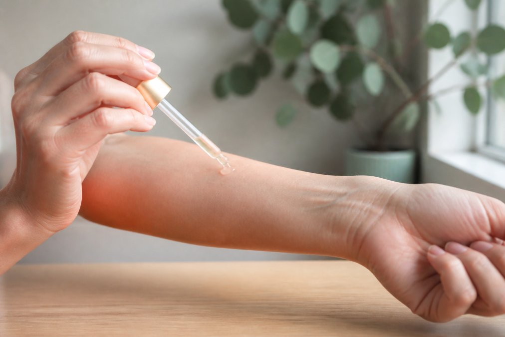 Nahaufnahme einer Hand, die ein Serum auf die Innenseite eines Unterarms aufträgt, mit natürlicher Beleuchtung und sauberer Haut