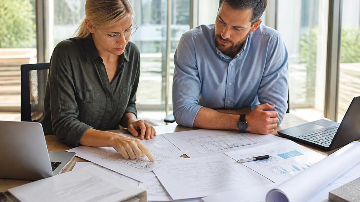 Architect and engineer reviewing energy modeling services reports at a desk