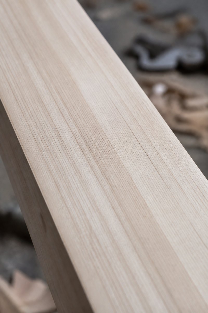 Close-up of English willow cricket bat face showing natural grain patterns and wood texture with warm natural lighting highlighting the grain structure
