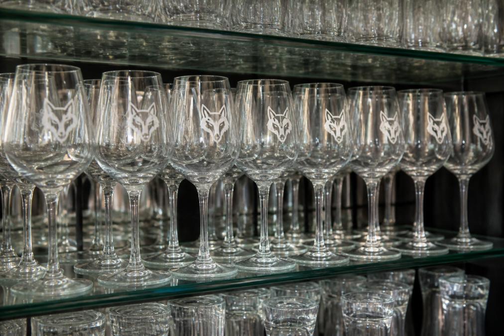 Multiple custom-printed or engraved glasses arranged in neat rows on a display shelf showing uniform colour and logo clarity across the entire batch under even lighting