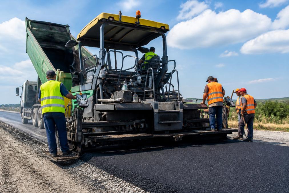 Construction crew operating an asphalt paver during paving equipment financing projects
