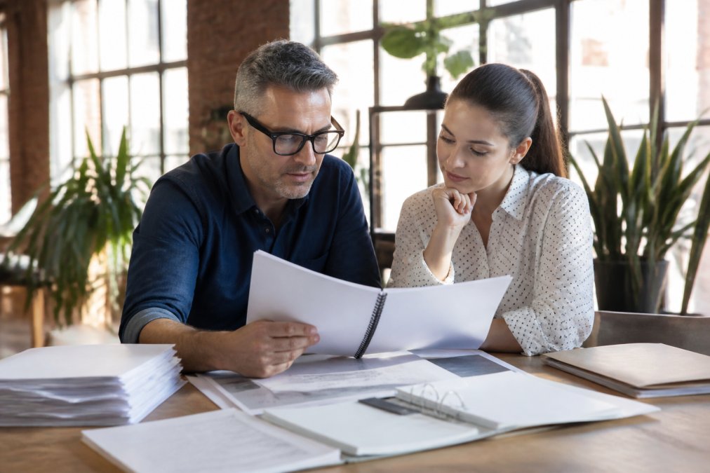Business owner and team member reviewing an operations manual while scaling a company in a bright office