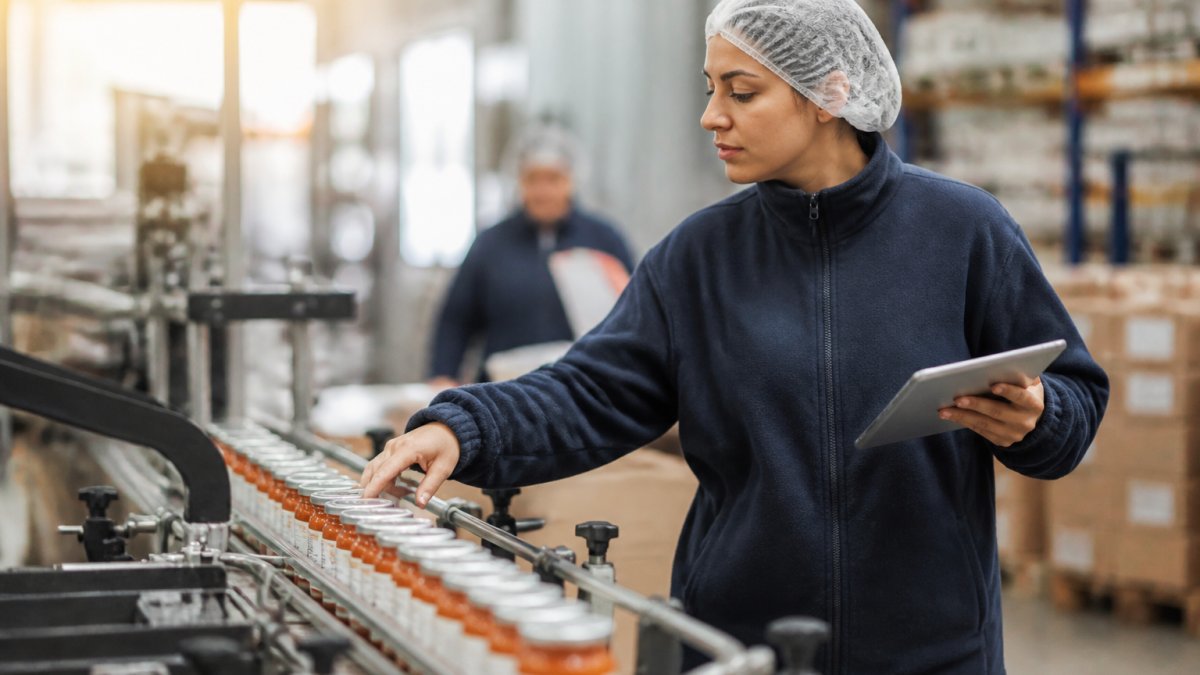 Operatore che controlla manualmente etichette su prodotti in una linea di confezionamento, verificando allineamento, leggibilità e completezza delle informazioni obbligatorie