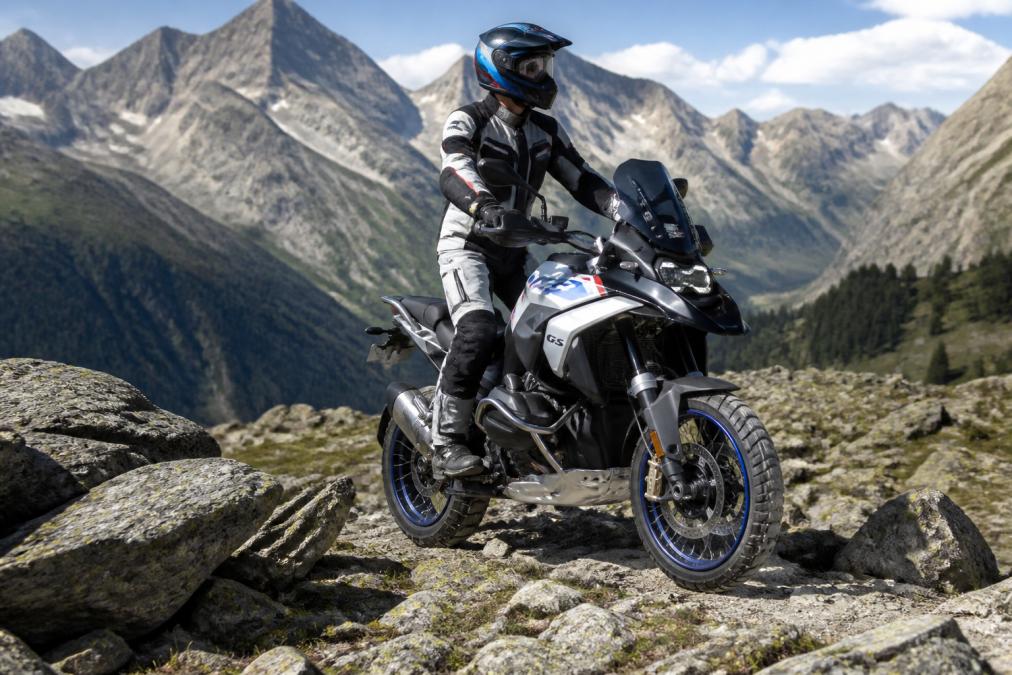BMW R1300GS M Performance in bergachtig terrein, rijder in volle veiligheidsuitrusting, toont adventure-capaciteiten in daglicht