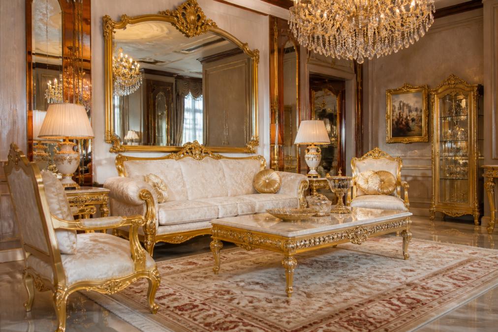 Luxuriöses Wohnzimmer mit eleganter barocker Einrichtung, großem goldenem Wandspiegel, weißem und goldenem Barocksessel, Kristalllüster und edlen Möbeln in klassischem Setting