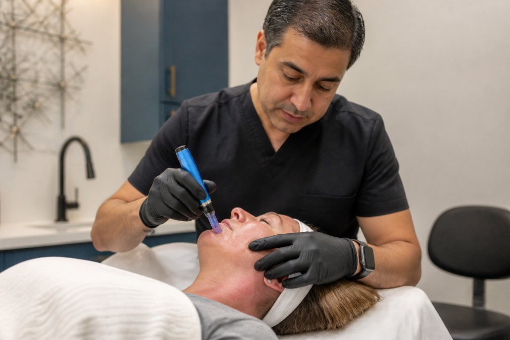 Professional dermatologist performing microneedling procedure on patient's face in modern clinical setting with precision equipment and professional lighting