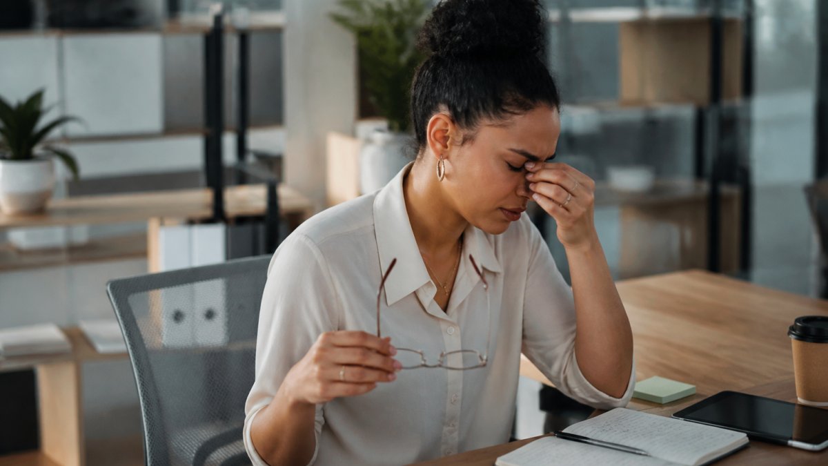 Office worker rubbing tired eyes while working at a computer, highlighting the difference between eye strain vs dry eye.
