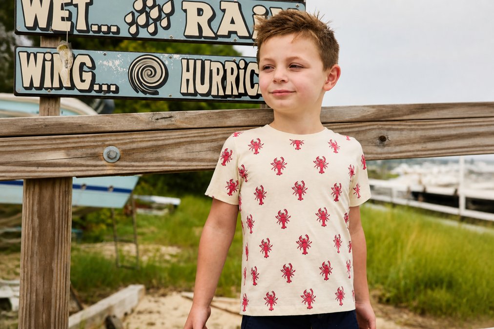 Young child wearing soft organic cotton t-shirt, relaxed posture, close-up showing smooth fabric texture and comfortable fit without visible seams or tags, natural daylight