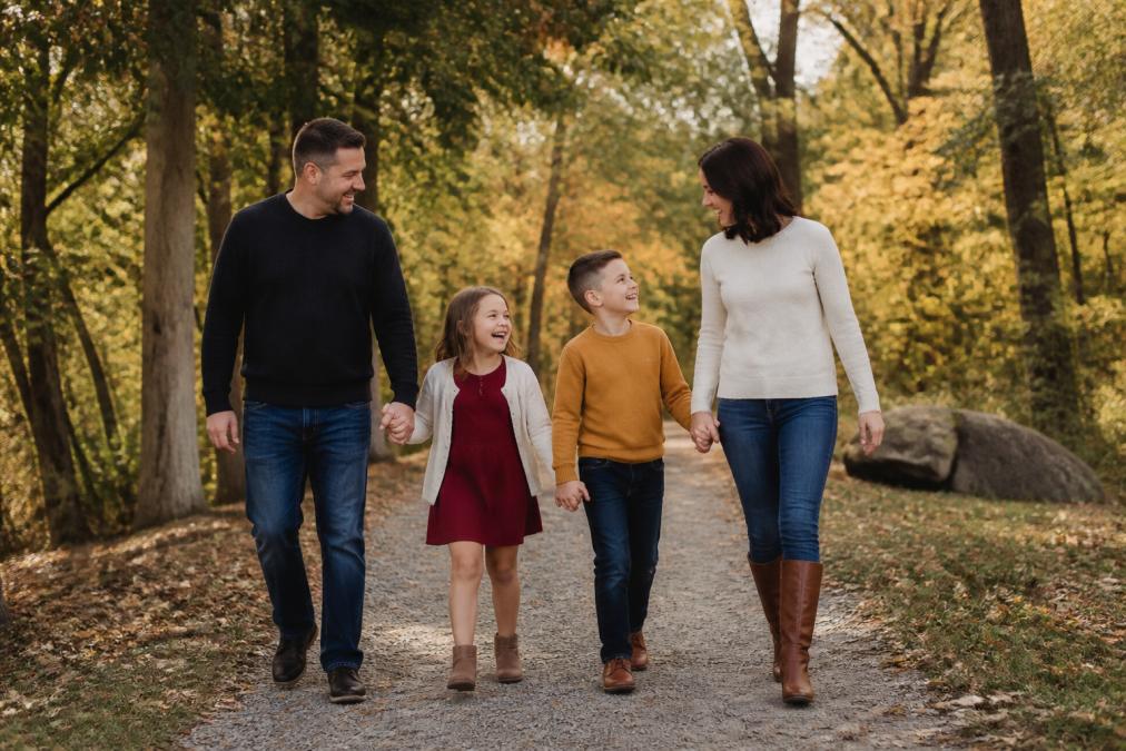 Family of four walking through a sunlit park during their fall family photos session