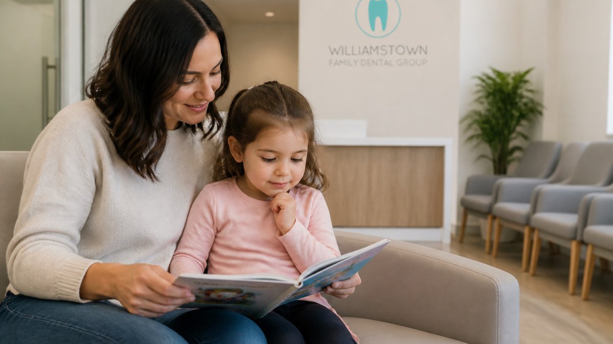A parent and child reading together in a calm waiting room for family dental care.