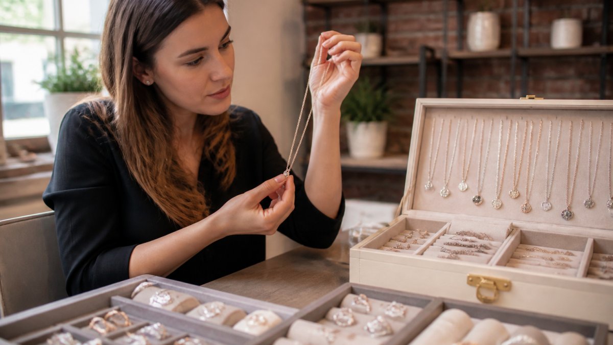 Person examining a piece of fast shipping personalized jewelry while holding it up to the light at a display
