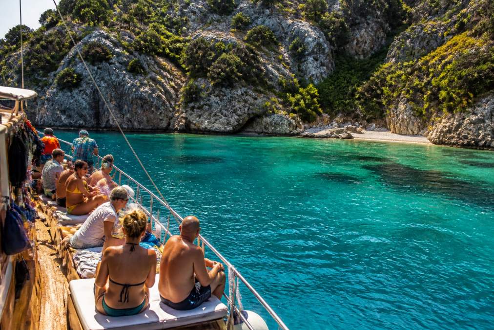 Fethiye'nin turkuaz koylarında ekonomik tur paketleri ile gezen turistler ve arkalarında görünen doğal kaya formasyonları