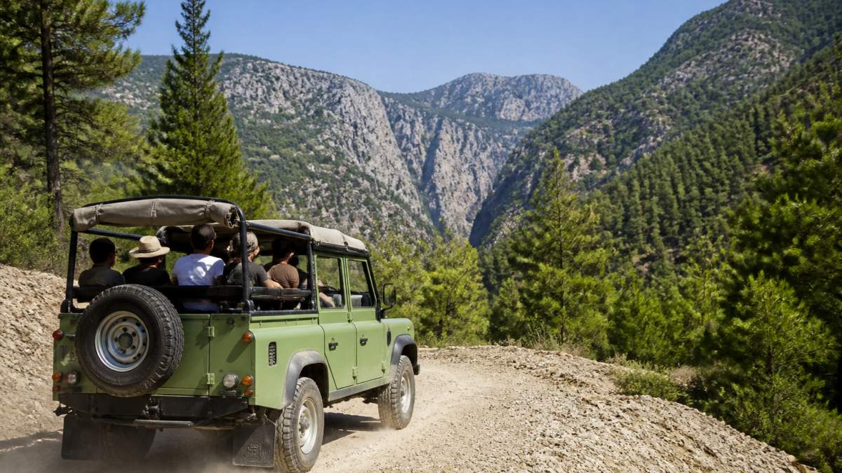 Açık yeşil bir jeep, Fethiye'nin tozlu dağ yolunda ilerliyor; arka planda çam ormanları ve uzakta Saklıkent Kanyonu'nun kayalık yamaçları görünüyor, güneşli bir yaz sabahı