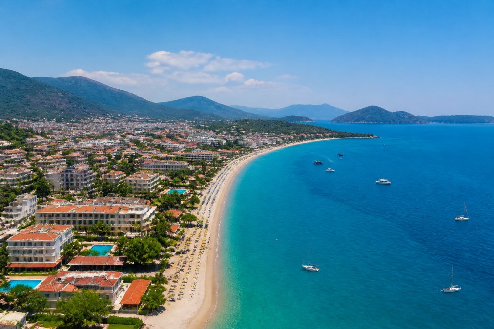 Fethiye'nin güneşli kıyı şeridi, plajlar ve otel binalarının yer aldığı panoramik görünüm, mavi deniz ufukta görülüyor