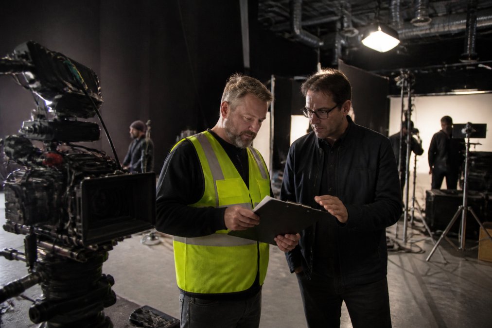 A safety consultant and director reviewing a clipboard on a soundstage to ensure film production safety.