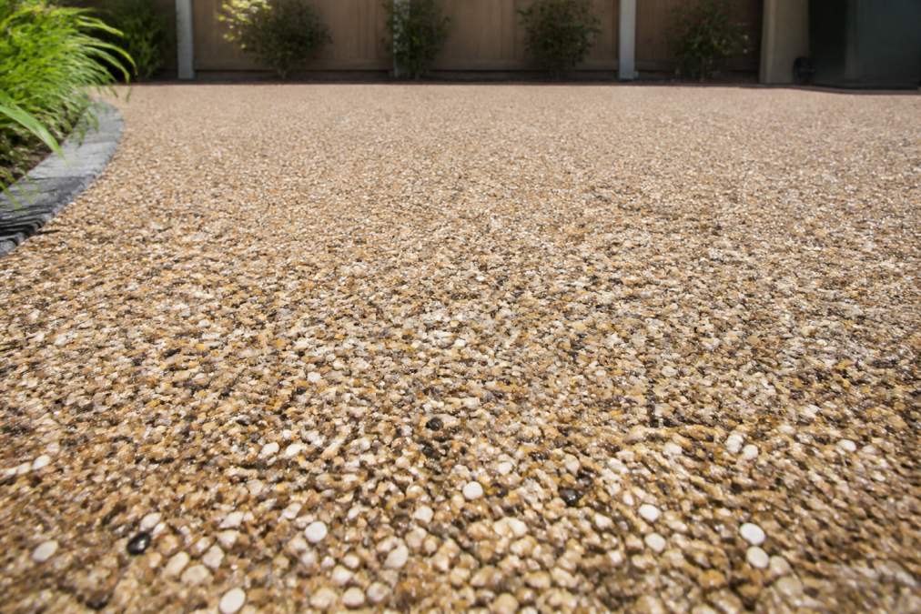 Close-up of a finished resin bound driveway surface with decorative aggregates, showing smooth texture and professional finish with natural light highlighting the detail