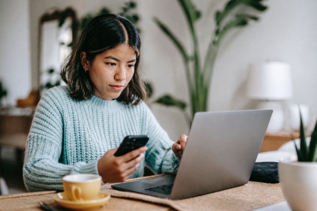 Person sitting at a desk with a laptop and phone, searching online for mental health services with a calm, focused expression
