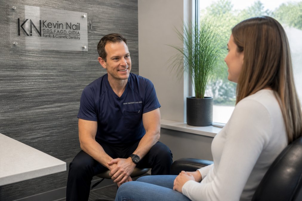 Dental professional having a calm, attentive conversation with patient in a relaxed clinical setting with soft natural lighting and comfortable seating