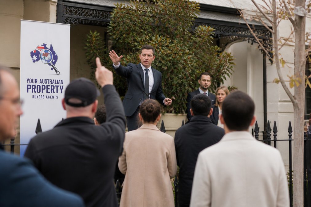 Auctioneer conducting property auction with multiple bidders in competitive bidding environment at Melbourne property