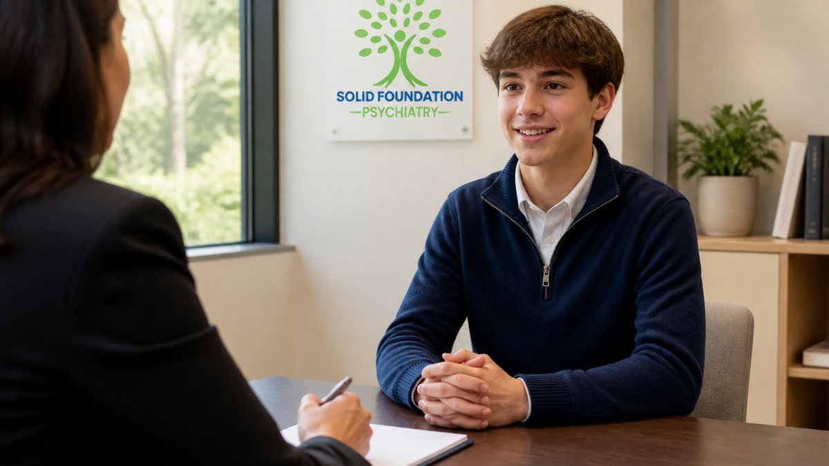 A confident teenager sitting at a table across from an interviewer in a professional office setting, making eye contact, wearing neat casual business attire, natural office lighting with a desk and window in background