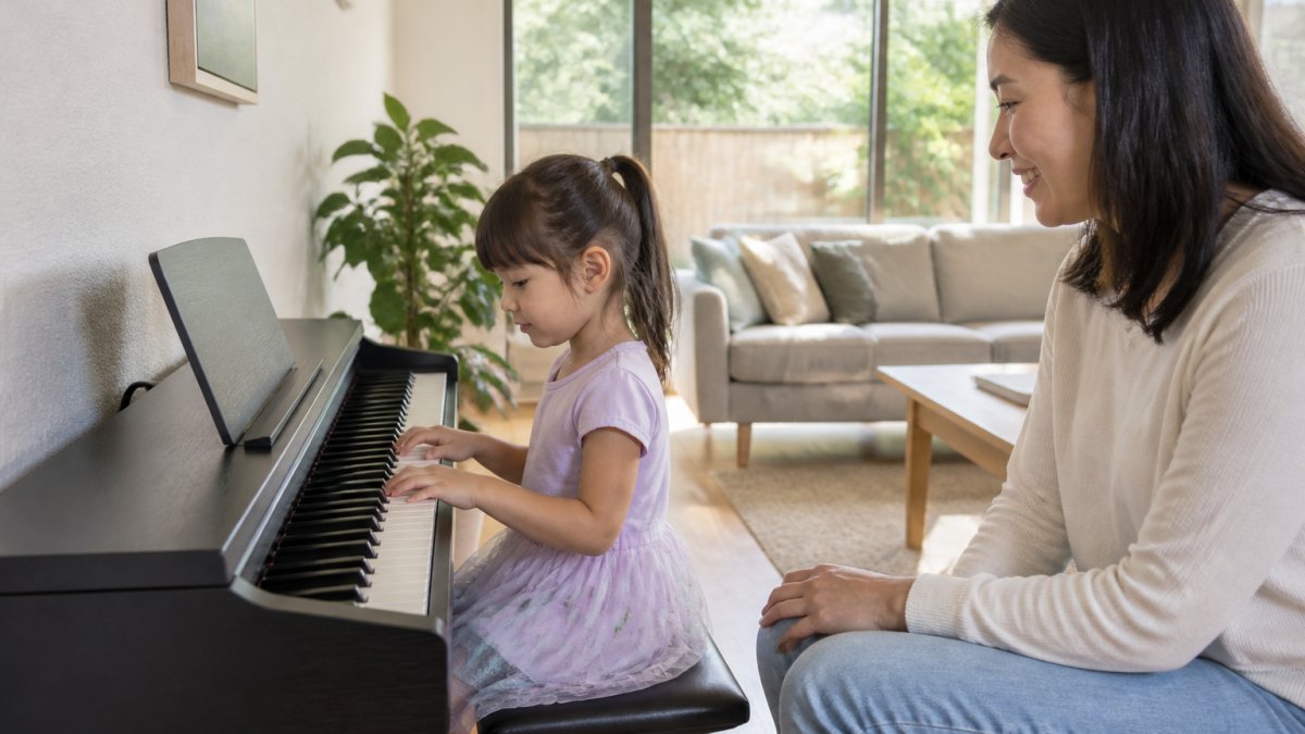 A five-year-old child sitting at a compact digital piano in a bright Australian living room, small hands resting on the keys while a parent watches nearby