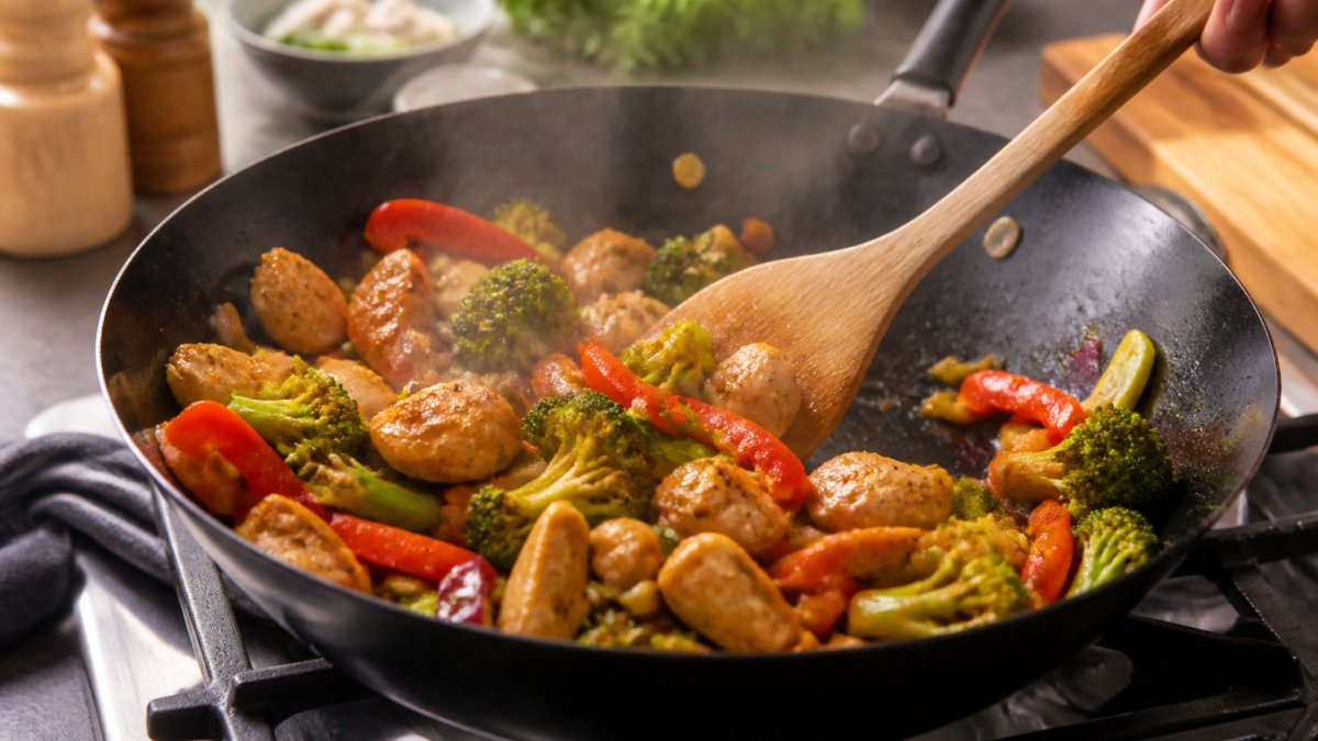 Step-by-step diagram showing the process of stir-frying chicken and fresh vegetables in a hot wok