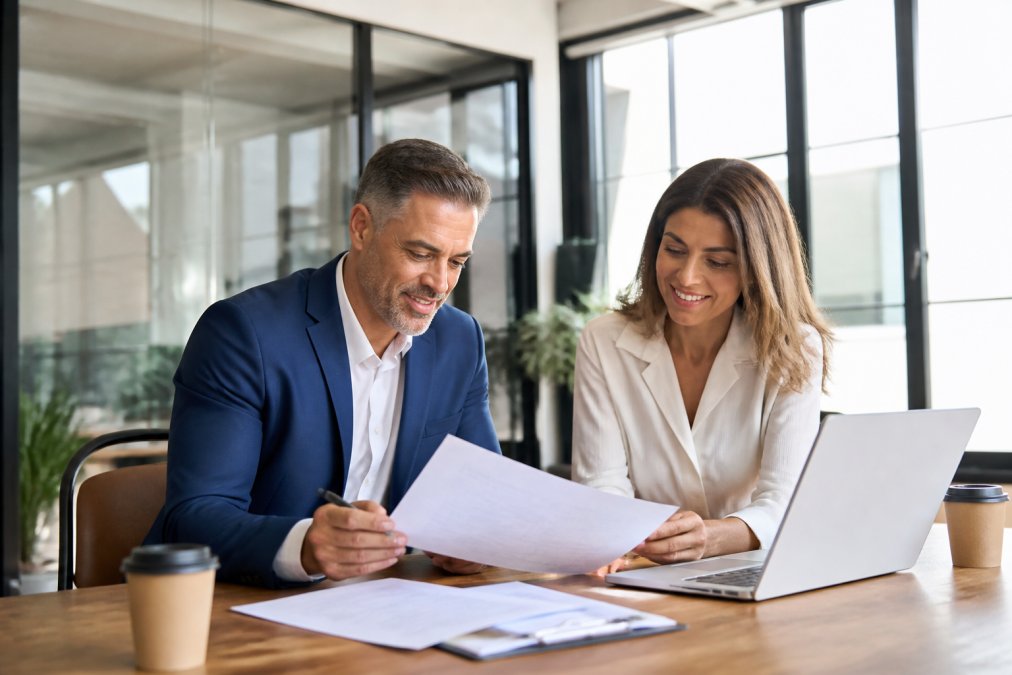 Business owner and HR consultant reviewing paperwork to discuss Florida PEOs in a sunlit office
