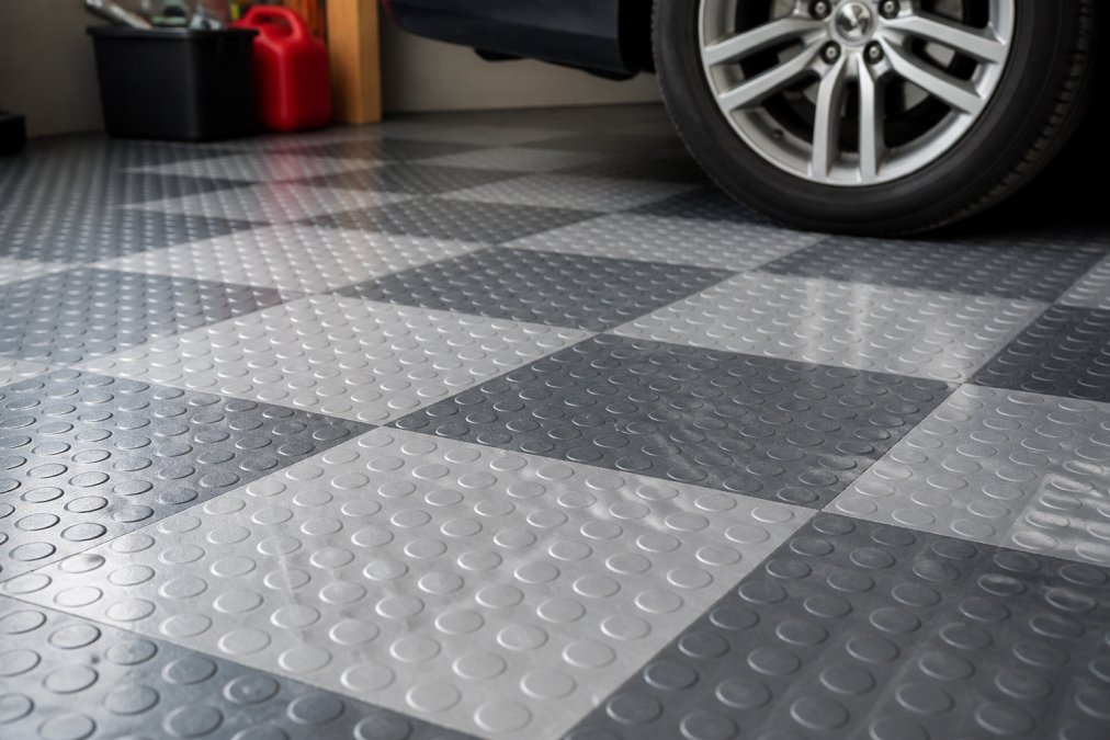 Closeup af løstliggende PVC-fliser på garagegulv, der viser teksturen, farverne og hvordan fliserne ligger sammen uden synlige sømme eller fuger