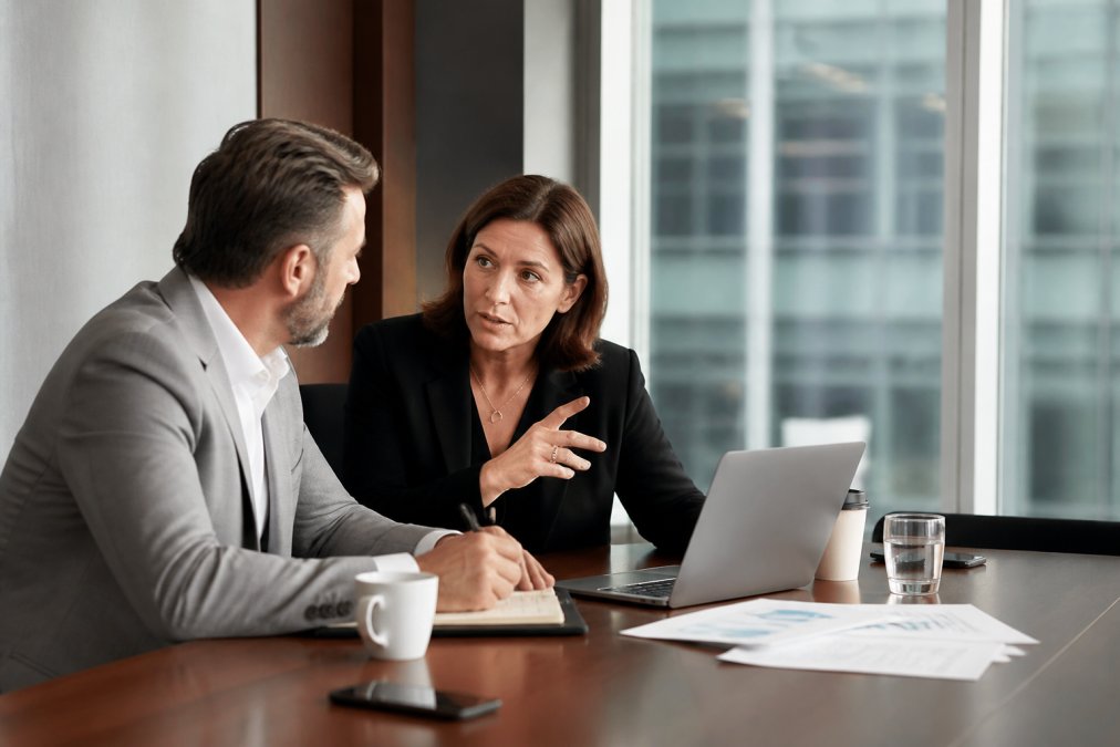 A marketing director and a business founder reviewing lead generation dashboards on a large monitor in a modern conference room, pointing at conversion metrics with focused expressions, natural window lighting