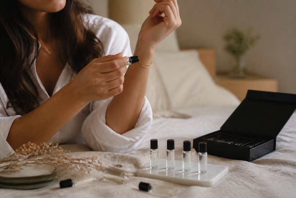 A person testing a sample vial on their wrist for a fragrance gift guide while others rest on linen.