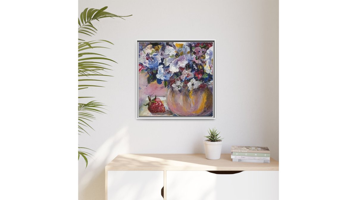 A sunlit living room wall featuring a framed matte canvas print of a floral still life, styled with a cozy reading nook and warm neutral tones