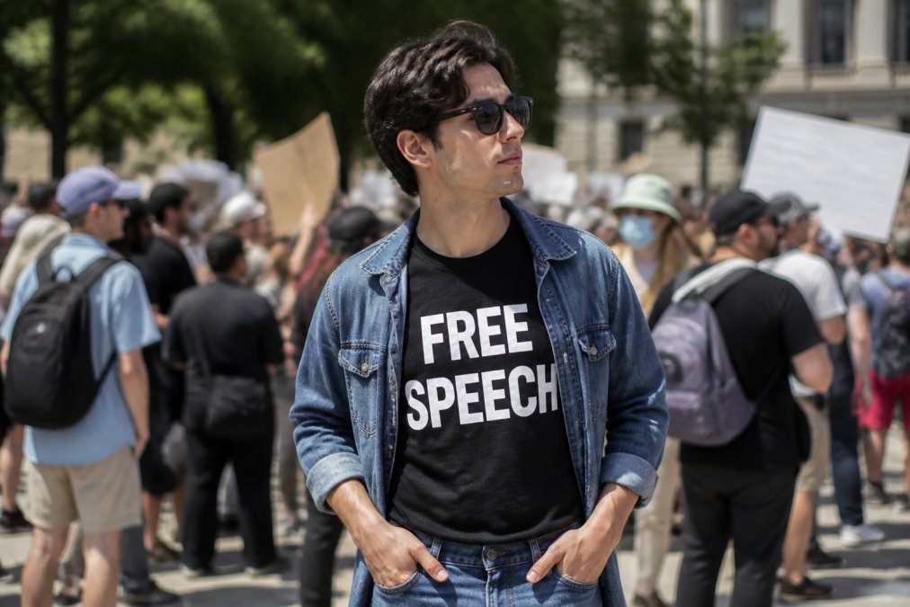 A person wearing a well-fitted free speech t-shirt styled with jeans and a casual jacket, ready for a march or public event, with clear visible messaging and natural outdoor lighting