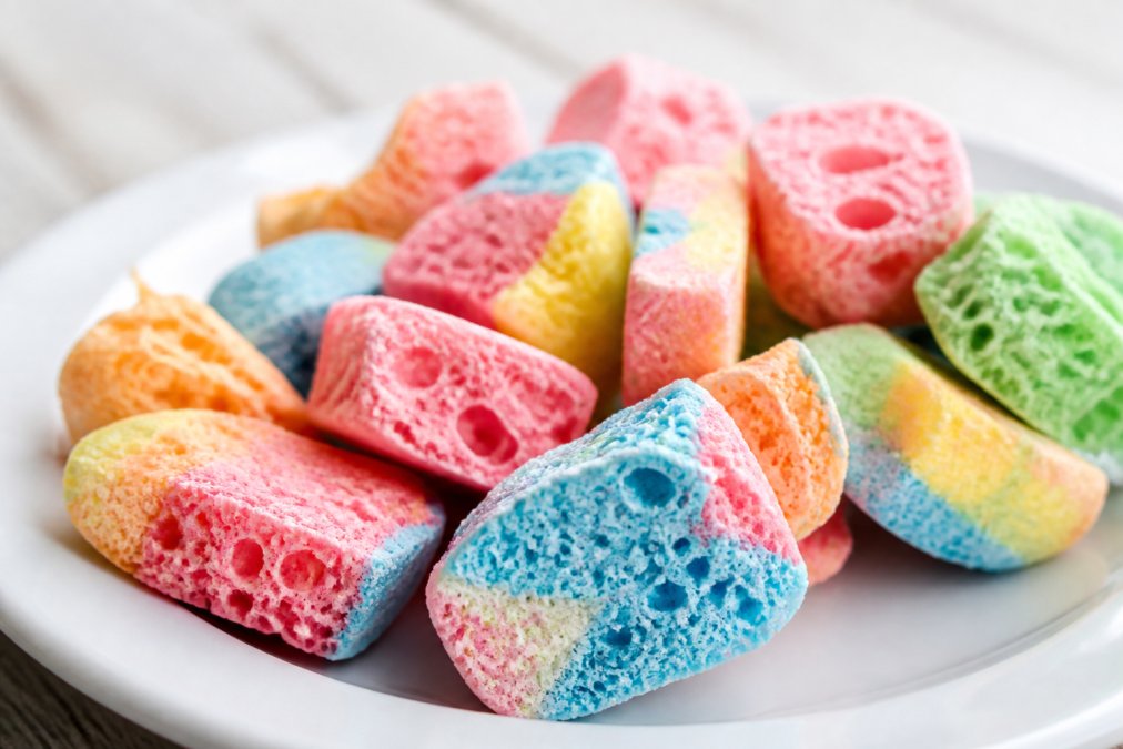 Colorful pieces of candy on a white plate displaying a light and airy freeze dried candy texture