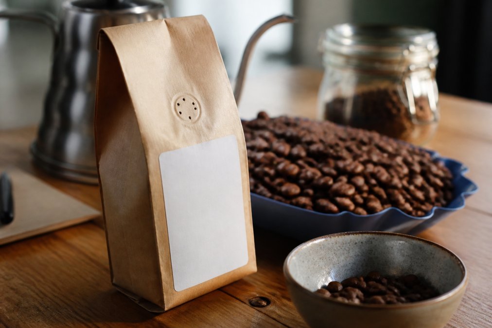 Close-up of a coffee bag label displaying roast date and freshness indicators with whole arabica beans visible in the background, natural morning light
