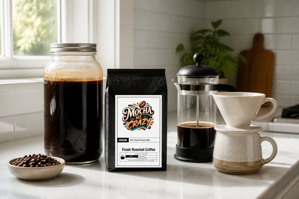 A glass cold brew jar filled with dark coffee concentrate steeping on a bright kitchen counter, alongside a French press and a ceramic pour-over dripper, all arranged neatly on a clean white marble countertop with soft natural light from a nearby window