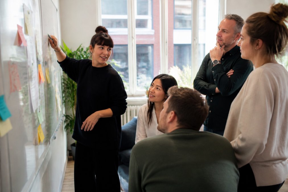 Diverse team collaborating on a full service digital marketing strategy at a whiteboard in a modern office