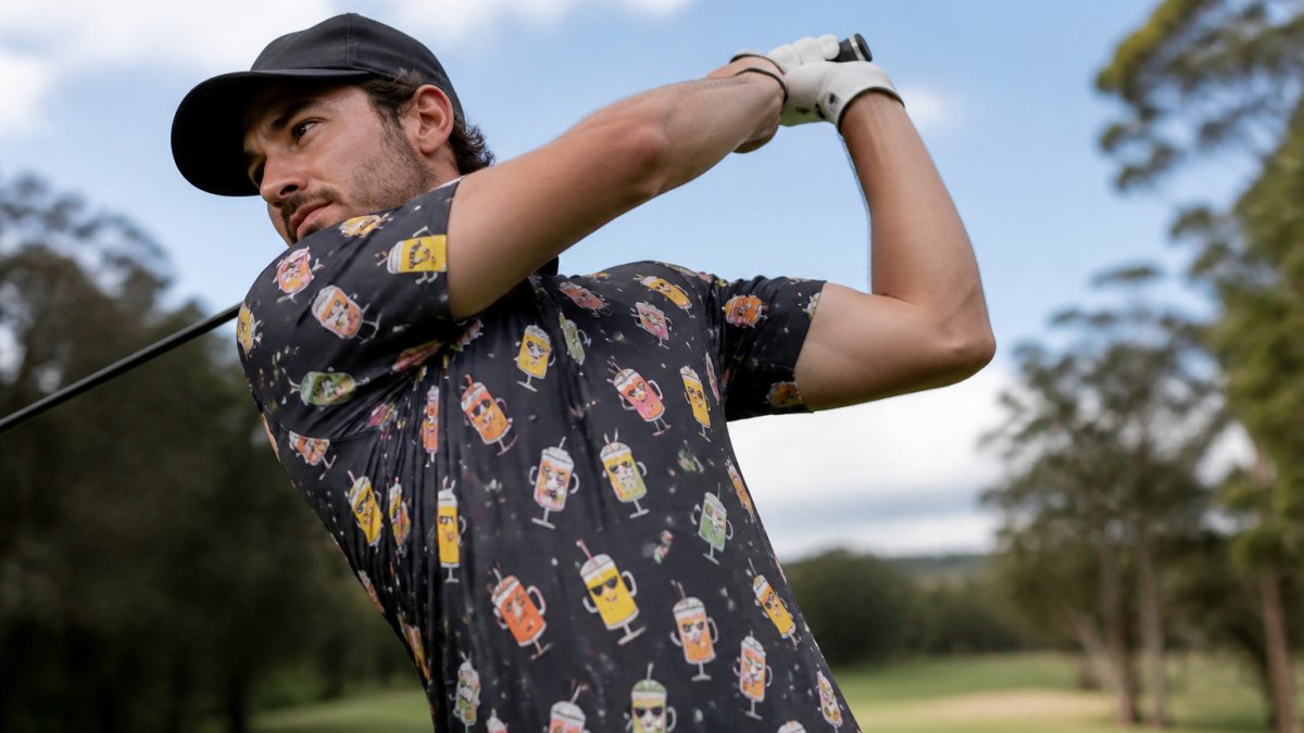 Close-up of golfer mid-swing wearing a funny golf shirt on the course, showing fabric texture, fit through the shoulders, and how the garment moves with the body