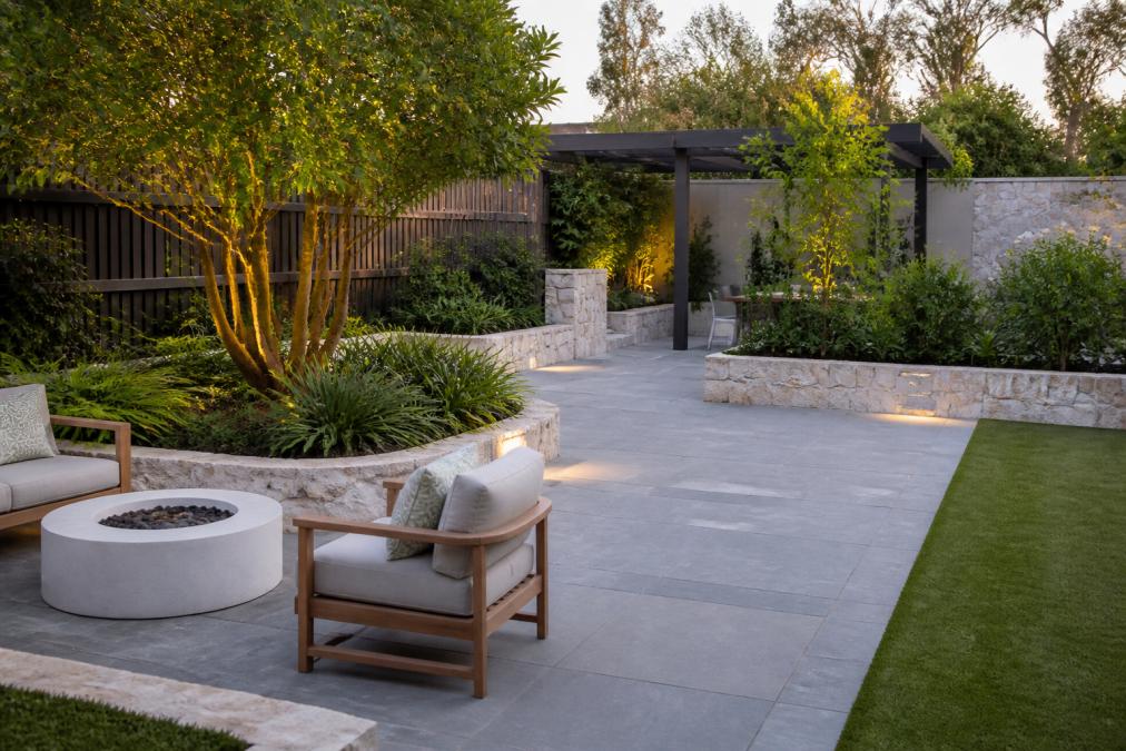A completed show garden at a sales centre featuring premium outdoor living space with quality paving, mature plantings, seating areas and well-maintained garden beds under natural daylight