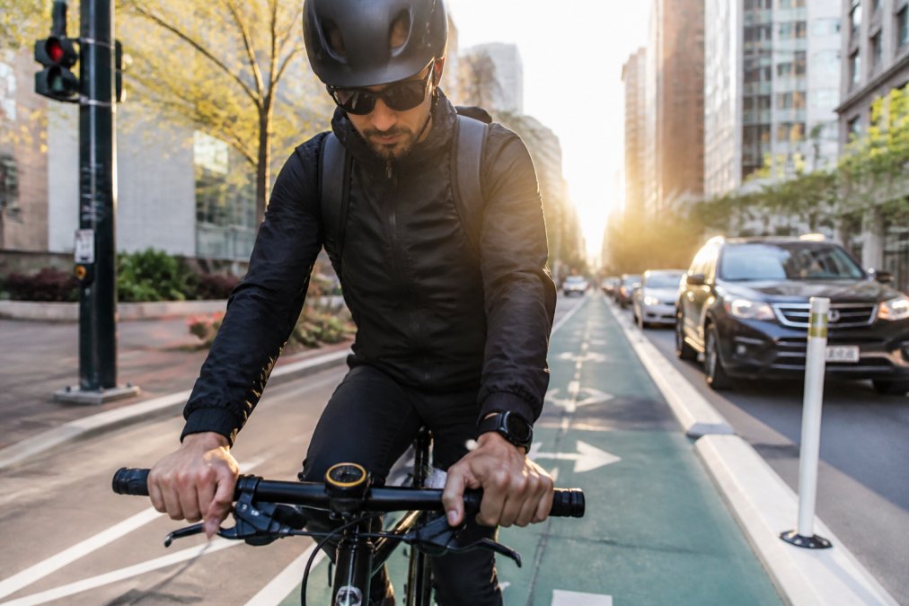 Casual cyclist checking a handlebar-mounted navigation device in an urban bike lane during the morning commute