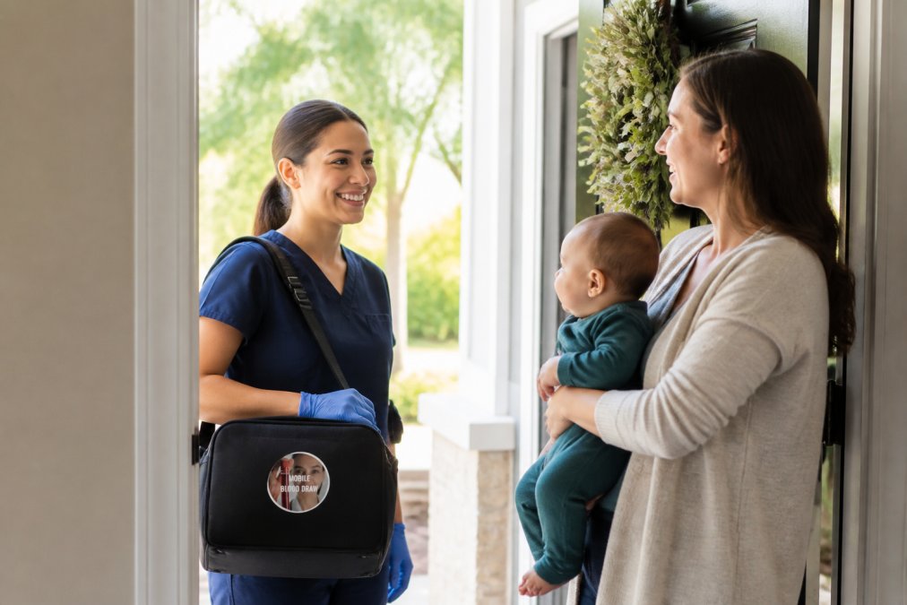 A professional phlebotomist in scrubs arriving at a bright, welcoming family home, carrying a medical kit, greeted at the front door by a smiling parent holding a young infant, morning sunlight coming through the entryway