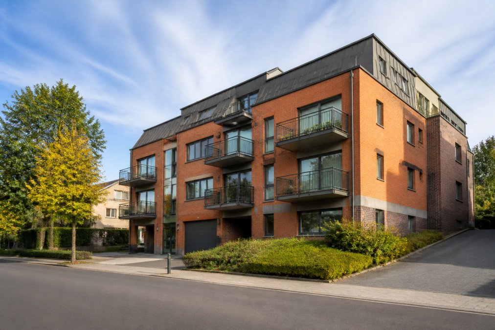 Vue extérieure d'un immeuble résidentiel moderne dans une zone urbaine, montrant la façade bien entretenue et l'environnement environnant