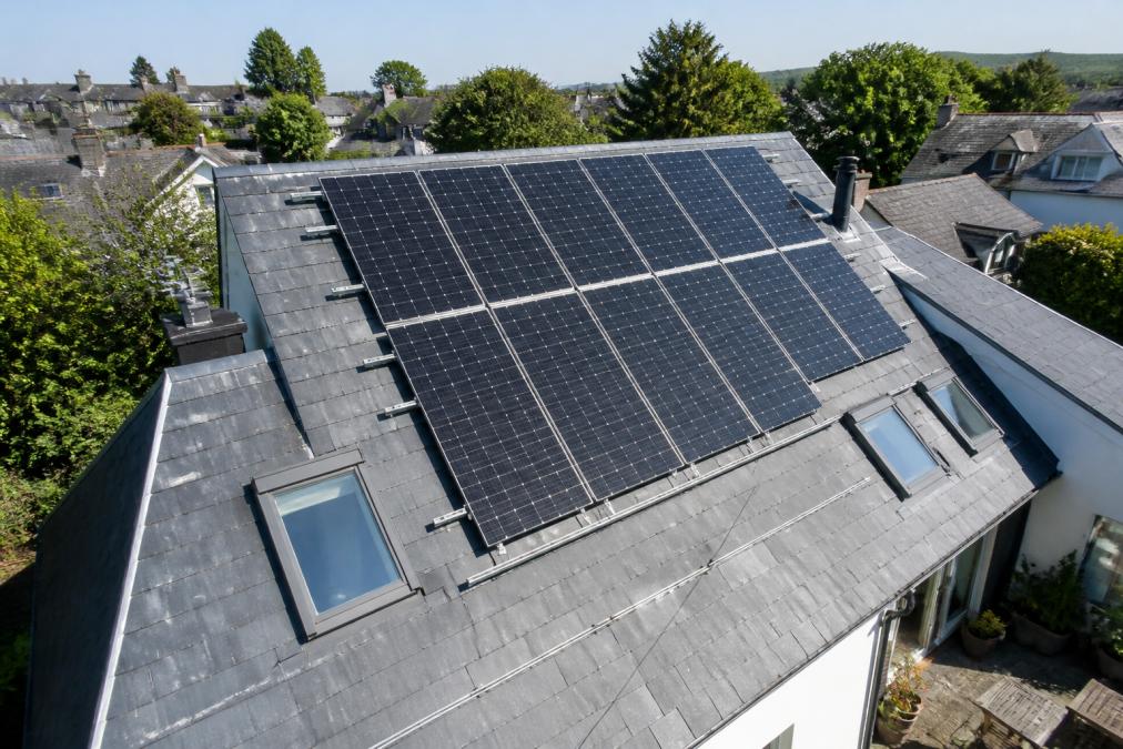 Aerial view of solar panels installed on a residential roof with clear southern exposure, showing the panels' optimal angle and spacing in bright daylight