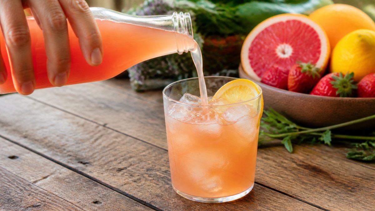 Infographic illustrating the step-by-step process of pouring a chilled fruit shrub soda over ice with citrus garnish